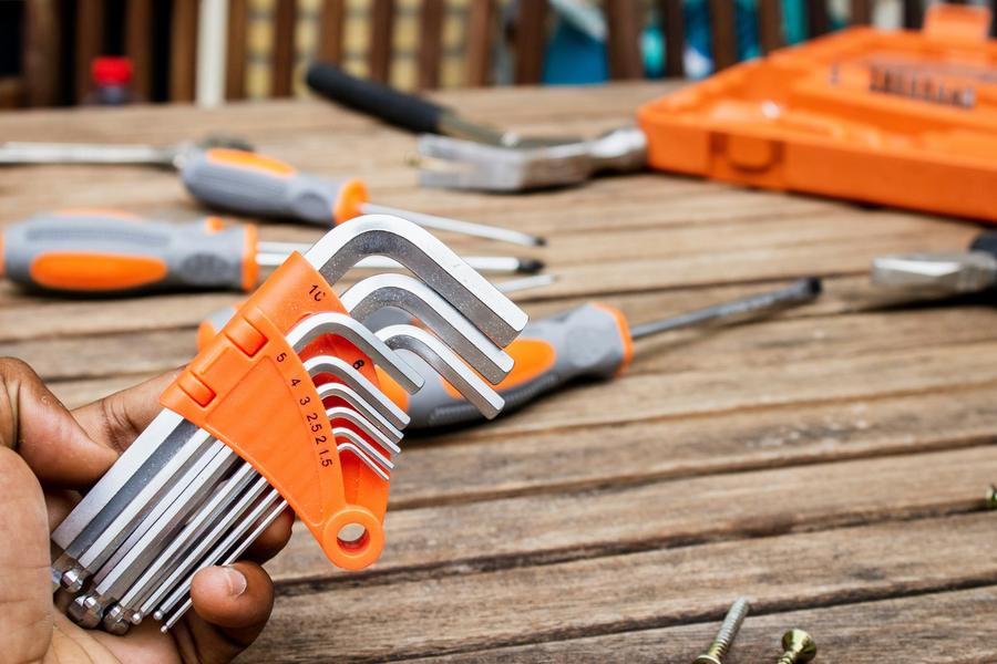 Hand holding a set of hex keys over screwdrivers on a workbench